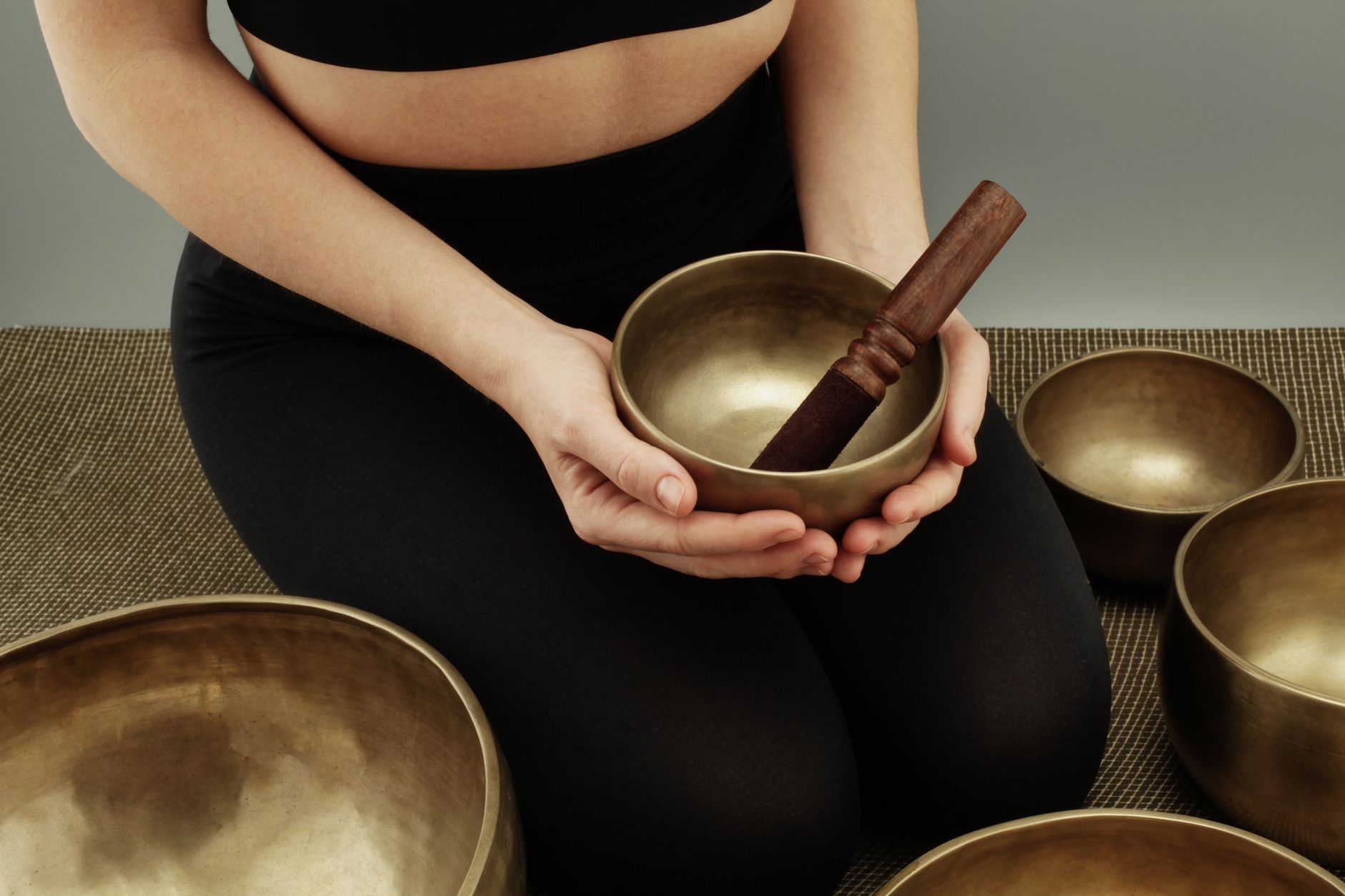 Sound therapy session with Tibetan singing bowls — practitioner rubbing mallet to generate harmonics