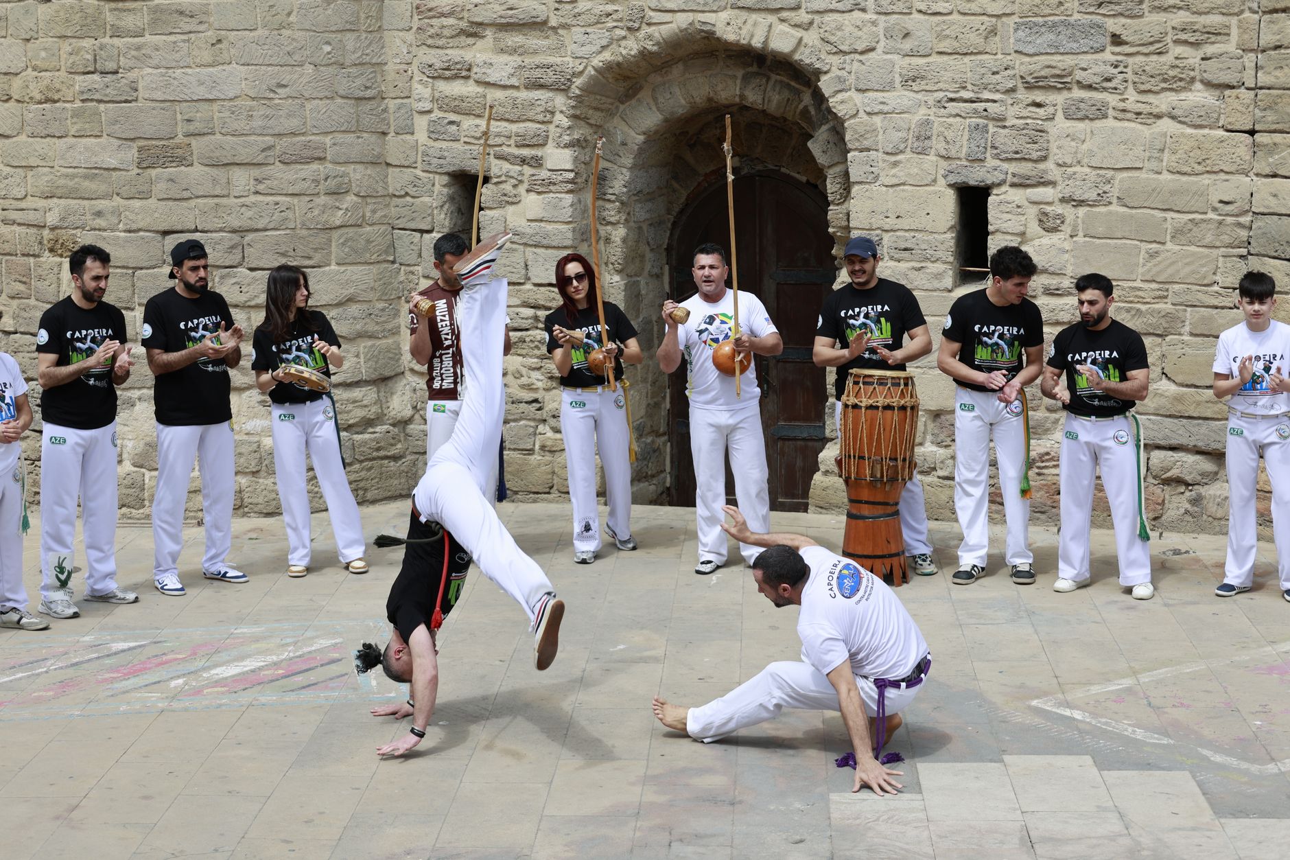Bateria de capoeira tocando berimbaus, pandeiro y atabaque alrededor de una roda