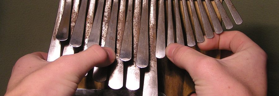 Manos tocando una mbira dzavadzimu tradicional de Zimbabue con los pulgares sobre las laminas metalicas